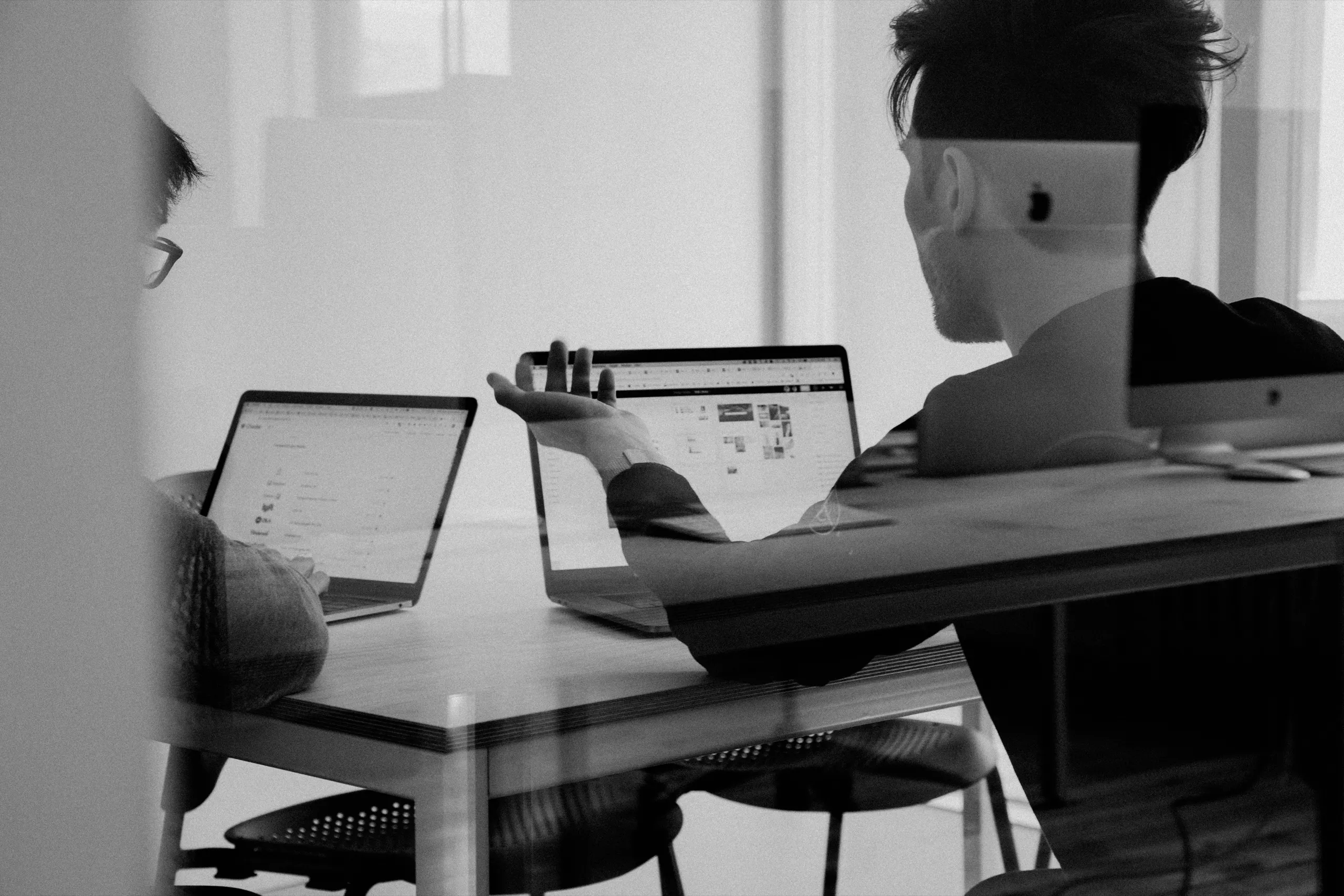 Two colleagues reviewing a matter on their laptops across a conference table